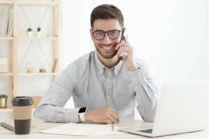 Businessman answering client phone calls with positive smile at office desk